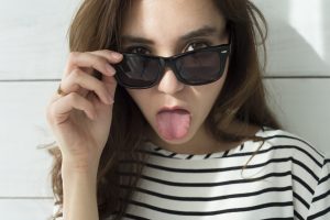Young woman with sunglasses has issued a tongue